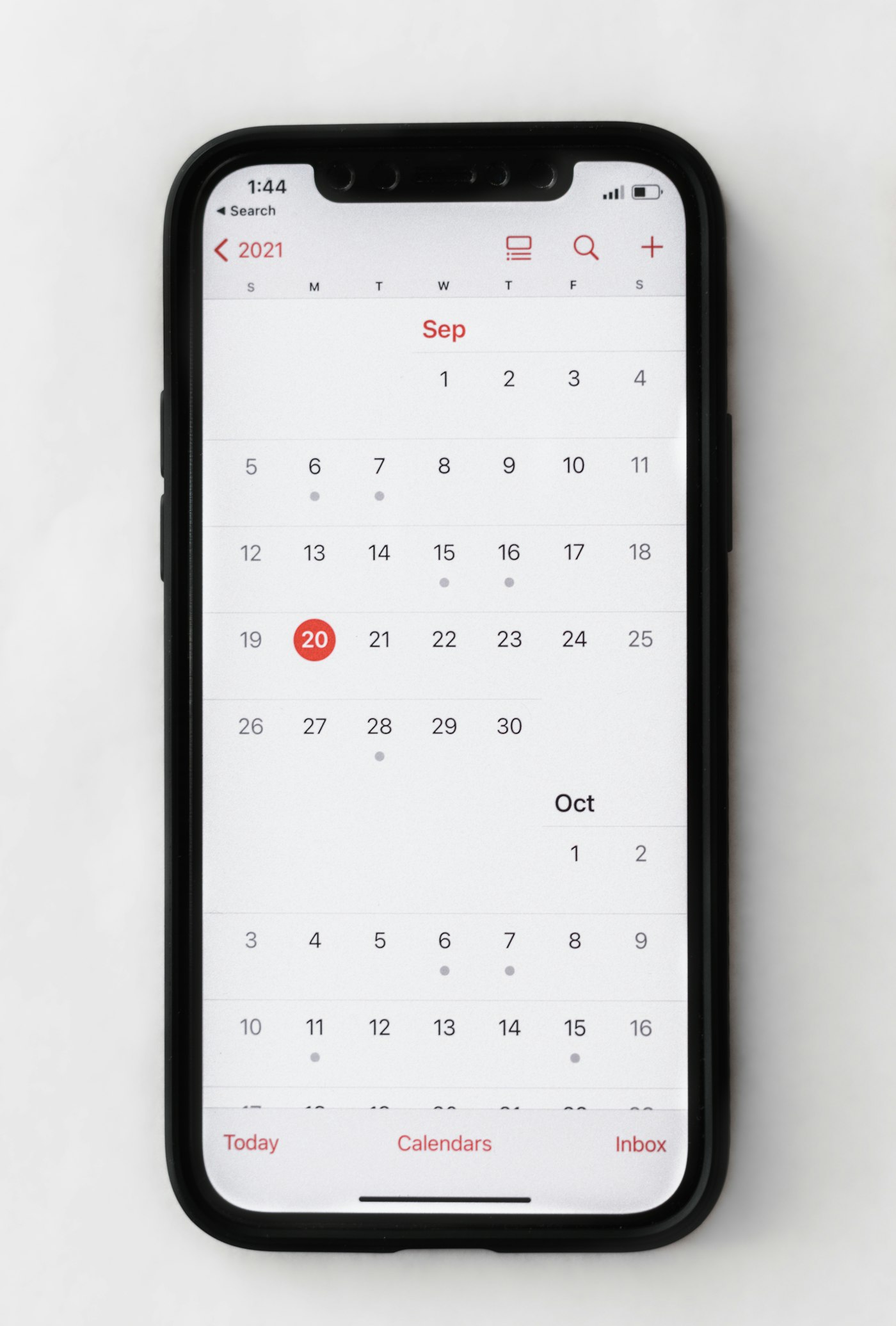 A phone lying flat showing a monthly calendar — the kind of view a scheduled posting queue lives in.
